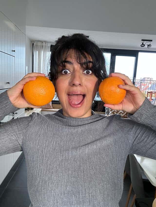 A photo of Ezgi with two oranges at each side of her head.